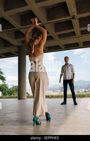 Couple dancing in an open pavilion. woman practicing in heels while partner watches during a romantic outdoor dance rehearsal Stock Photo
