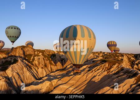 Colorful hot air balloons float above the unique rock formations of Cappadocia during sunrise. Stock Photo