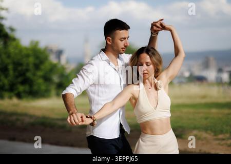 Couple dancing outdoors in a park: partners practicing a graceful partner dance with relaxed summer style and connection Stock Photo