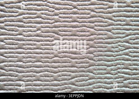 Close-up of quilted mattress texture showing wavy padded pattern on neutral beige fabric surface Stock Photo