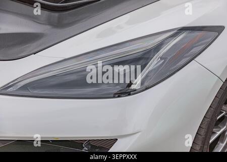 Modern car headlight assembly, sleek angular design, high-quality transparent lens, white housing finish, smooth glossy texture, well-maintained surfa Stock Photo