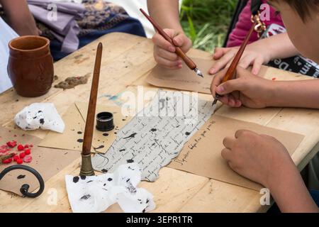 Moscow, Russia - June 12, 2025: kids calligraphy master class, dip ink pens. Children participate in historical reenactment, writing with quills and i Stock Photo