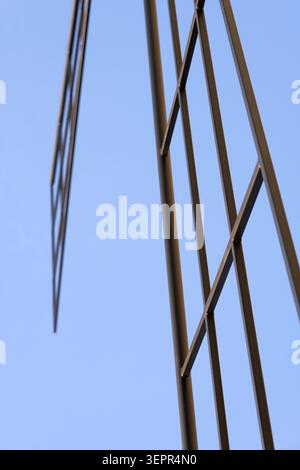 Metal framework forming an abstract geometric grid against a clear blue sky, conveying modern architecture, strength, progress and industrial design f Stock Photo