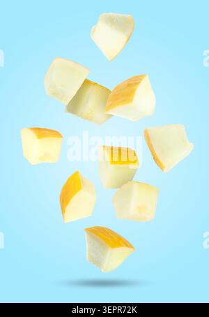 Sweet melon pieces falling against light blue background Stock Photo