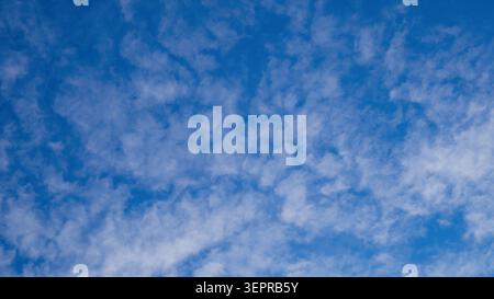 Panoramic view of wispy white clouds spreading across blue sky. Natural cloudscape texture background on bright day Stock Photo