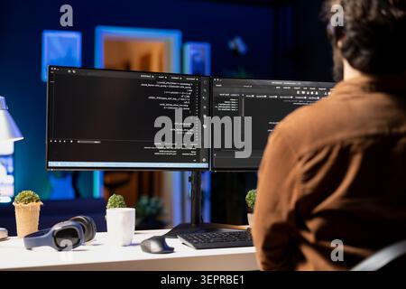 Man working from home implementing security measures to protect company systems and data; tech support IT worker writing, testing and debugging code for software applications. Stock Photo