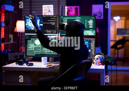 Hacker wearing VR headset uses AI machine learning to develop zero day exploit undetectable by antivirus; rogue engineer uses virtual reality and neural networks to build script doing data mining. Stock Photo