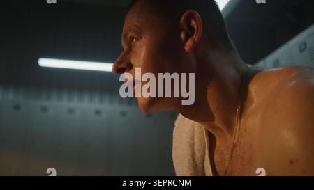 Young Male Athlete with Prosthetic Leg Resting in Gym Locker Room After Shower. Covered with Droplets of Water, Man Wipes Face with White Towel, Showcasing Mix of Fatigue and Deep Satisfaction. Stock Photo