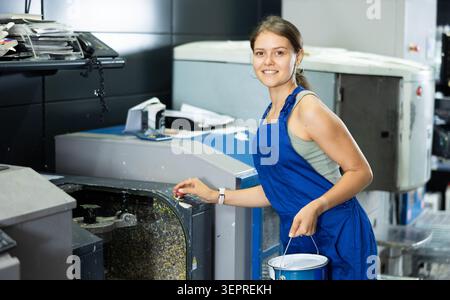 Woman in uniform operating computerised machne to mix paint Stock Photo