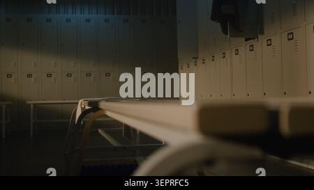Determined Young Man with Prosthetic Limb Prepares for Workout by Tying Shoelaces on White Sneaker in Sports Club Dressing Room. Concept of Resilience, Diversity, Real People, Daily Routine. Handheld. Stock Photo
