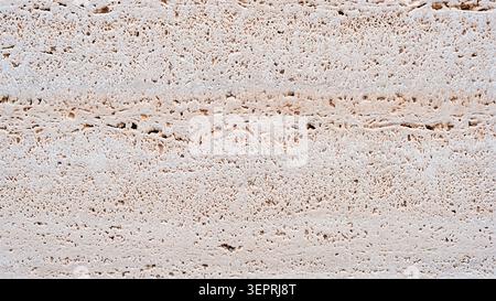 Natural travertine stone surface with porous texture and layered patterns. Detailed beige mineral background for architectural and interior design use Stock Photo