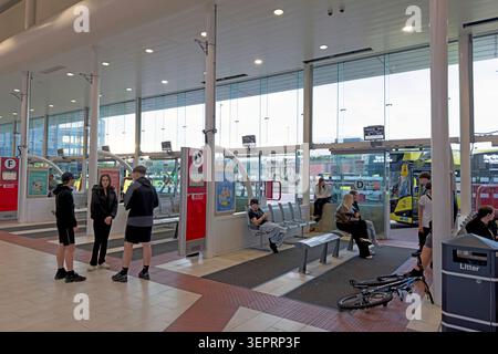 Passengers wait for early evening bus services inside Warrington Bus Interchange in the town centre, Cheshire, England, UK. Stock Photo