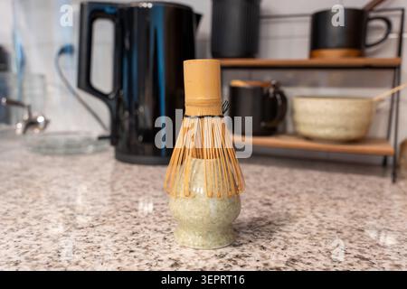A bamboo matcha whisk resting on a speckled granite countertop, highlighting traditional Japanese tea preparation tools in a modern minimalist kitchen Stock Photo