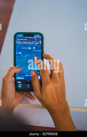 Balikpapan, Indonesia - May 31 2026. Hands holding a mobile phone in a dark green case over a white table. Stock Photo