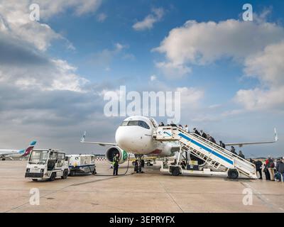 VALENCIA, SPAIN - MARCH 1, 2026: passengers board an Airbus A320neo on the tarmac at Valencia Airport using mobile stairs, with ground service vehicle Stock Photo