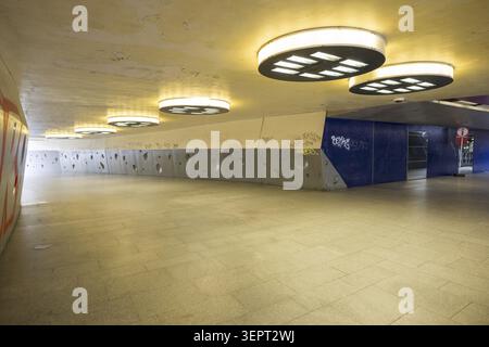 Gloomy underpass on Wiener Platz in Cologne-Muelheim, characterized by cold concrete, circular wall structures and yellowish ceiling lights. The tunne Stock Photo