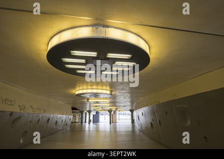 Gloomy underpass on Wiener Platz in Cologne-Muelheim, characterized by cold concrete, circular wall structures and yellowish ceiling lights. The tunne Stock Photo