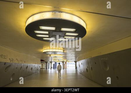 Gloomy underpass on Wiener Platz in Cologne-Muelheim, characterized by cold concrete, circular wall structures and yellowish ceiling lights. The tunne Stock Photo
