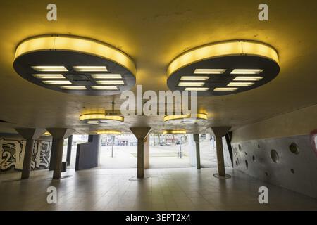 Gloomy underpass on Wiener Platz in Cologne-Muelheim, characterized by cold concrete, circular wall structures and yellowish ceiling lights. The tunne Stock Photo