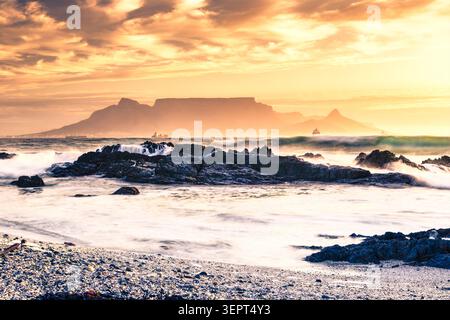 Setting sun over Table Bay in Cape Town, South Africa, taken from Bloubergstrand during Golden Hour. Dramatic sky creates atmospheric scene. Stock Photo