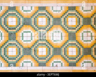 Abstract vintage ceramic tile wall with repeating geometric octagon and square motifs in green, yellow and white, creating a retro decorative backgrou Stock Photo