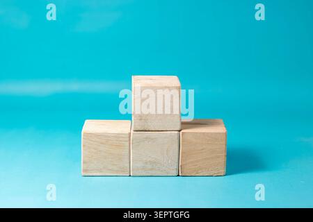 Four blank wooden blocks stacked in a pyramid shape creating a podium concept against a solid blue backdrop. High Quality Photo Stock Photo