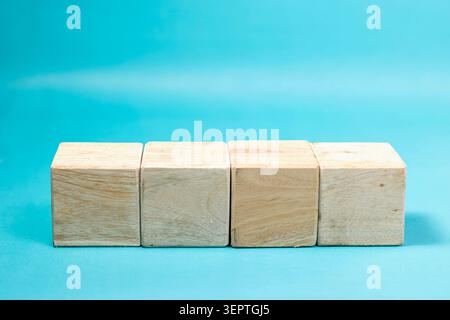 Four blank wooden blocks placed side by side in a straight horizontal line against a vibrant blue background. High Quality Photo Stock Photo