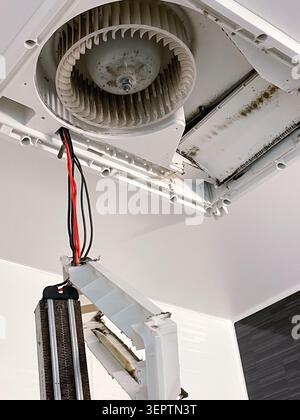 An opened wall-mounted air conditioner reveals fan blades, heat exchanger, and wiring with visible dust and mold buildup. A common sight in Japanese rental apartments requiring professional cleaning before or after hikkoshi (moving day). Stock Photo
