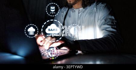 User interacts with Saas platform using laptop in a dark room at night Stock Photo