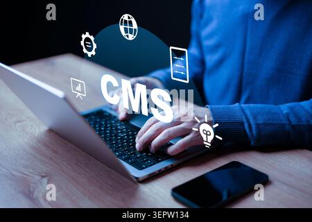 Working on a content management system at a desk with a laptop and smartphone Stock Photo