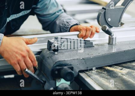 Carpenter works on furniture in workshop using saw machine during the day Stock Photo