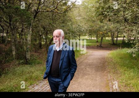 Senior man slowly walking contemplative along a path through the park Stock Photo