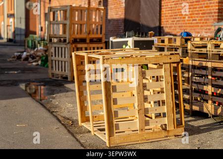 Industrial wooden boxes used for shipping goods left outdoors on the pavement near a brick warehouse back alley Stock Photo