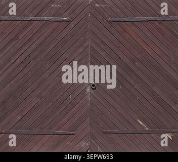 Large double barn door crafted from dark brown wooden planks arranged in a distinctive chevron or herringbone pattern, Estonia, Europe. Stock Photo