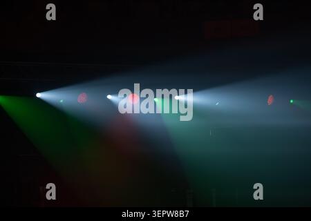 Stage spotlights pierce smoky air, colored beams sweep across empty stage, dramatic concert and theater lighting mood. Stock Photo