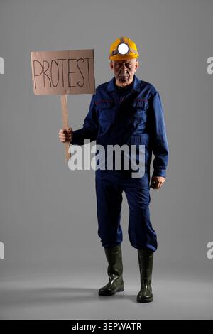 Protesting miner man with placard on grey background Stock Photo