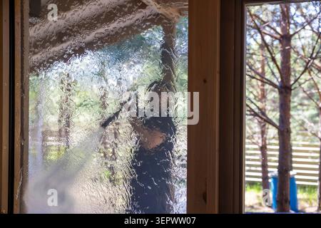 Man washing panoramic windows of modern house with high pressure water. Concept: window cleaning service Stock Photo