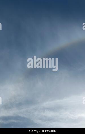 Rare optical phenomenon known as a reverse rainbow. Sun light refracting through ice crystals in high altitude cirrus clouds. Ideal for meteorology, s Stock Photo