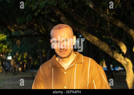 Happy Smiling Man with Hair Transplant Standing in Park at Sunset Stock Photo