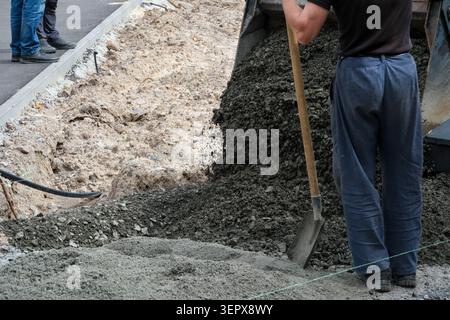 Construction crew is busy pouring fresh concrete into a newly dug trench. Stock Photo