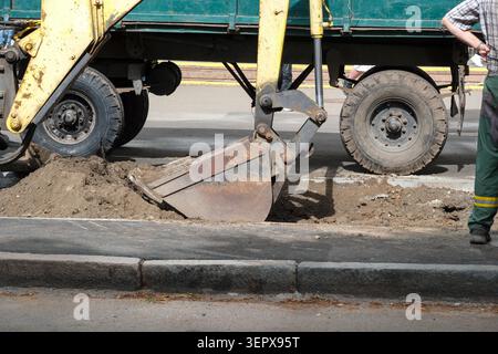 Excavator digs into the ground during a street repair project in progress. Kyiv, Ukraine, June 16, 2026 Stock Photo