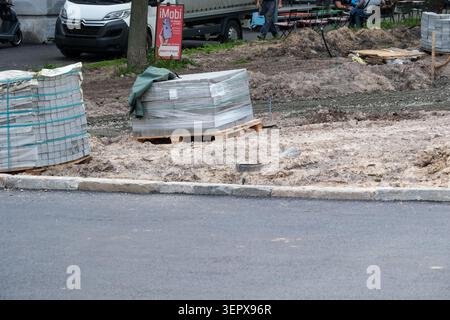 Materials stacked and construction underway on a bustling city street with vehicles. Kyiv, Ukraine, June 16, 2026 Stock Photo