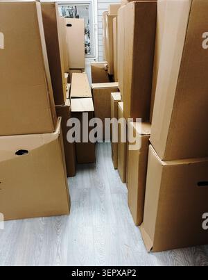 Large number of cardboard boxes stacked inside a storage room or warehouse. Logistics, moving and inventory management concept. Stock Photo