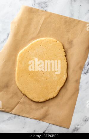 Process of making a base for shortbread pie, tart or quiche. The dough lying on parchment for rolling. Home baking culinary concept, recipe. Flat lay Stock Photo