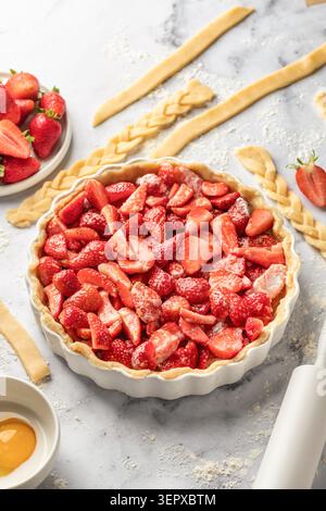 Process of making strawberry shortbread pie. Raw strawberry pie on white marble background. Home baking culinary concept, recipe Stock Photo