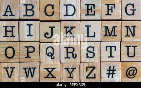 English alphabet on wooden blocks background top view. Full set of English letters from A to Z with hashtag and at symbols on wooden cubes texture bac Stock Photo