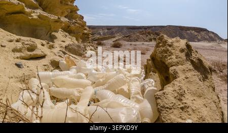 Dump of old plastic bottles sun-burned in the desert in the desert between stones on a background of mountains Stock Photo