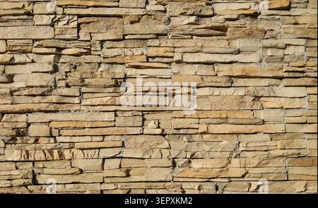 tone cladding wall made of striped stacked slabs of natural brown rocks. Background and texture. Stock Photo