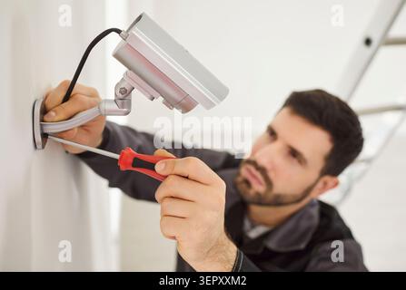 Professional service man installing security camera, using screwdriver tool, fastening mount to wall Stock Photo
