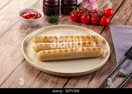 Three grilled sausages with golden brown spots served on a beige ceramic plate Stock Photo